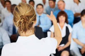 Rear view of a female spokesperson giving a presentation to her colleagues